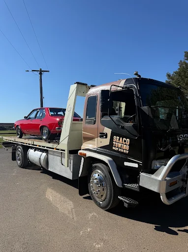 Classic red Torana loaded on the Seaco tilt tray on a clear day
